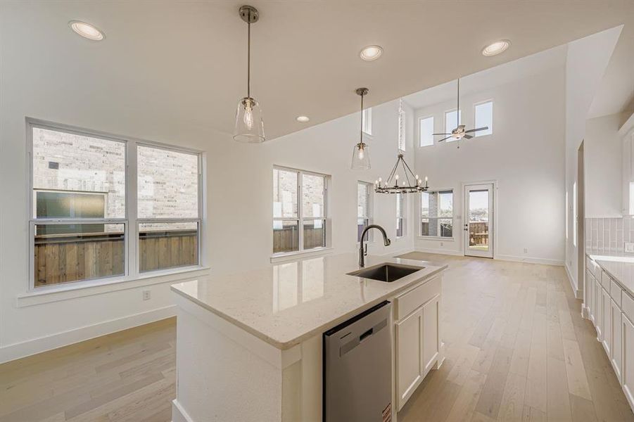 Kitchen featuring white cabinets, decorative light fixtures, recessed lighting, dishwasher, and a center island with sink