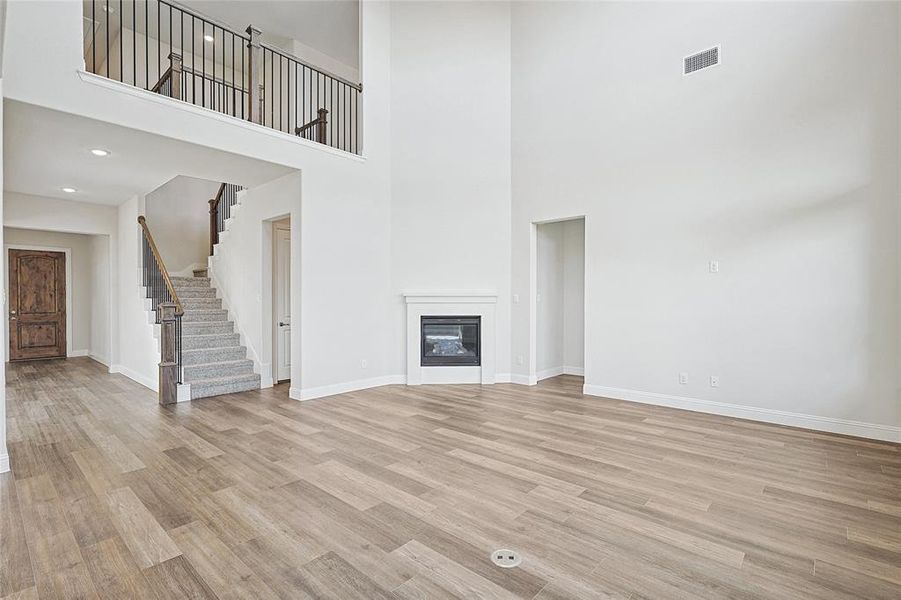 Unfurnished living room featuring light hardwood / wood-style floors and a high ceiling