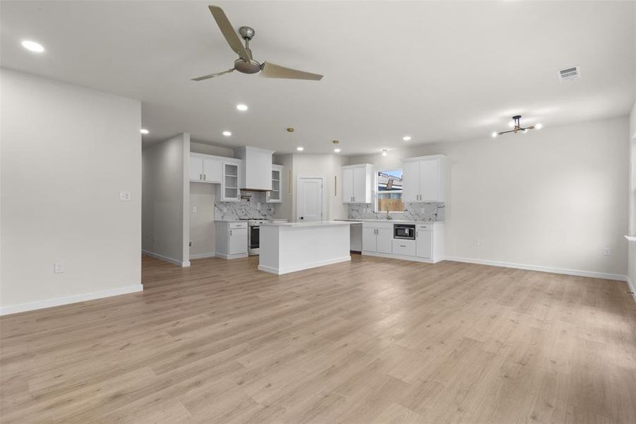 Open-concept living area featuring light wood-finish flooring, recessed lighting, and a contemporary ceiling fan