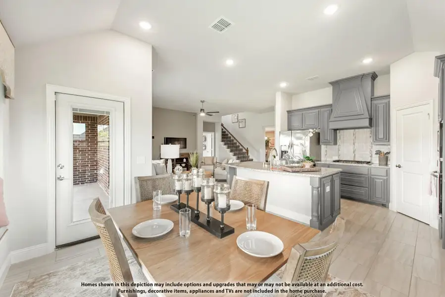 Open dining area with wood table flowing into kitchen with gray cabinets and large island