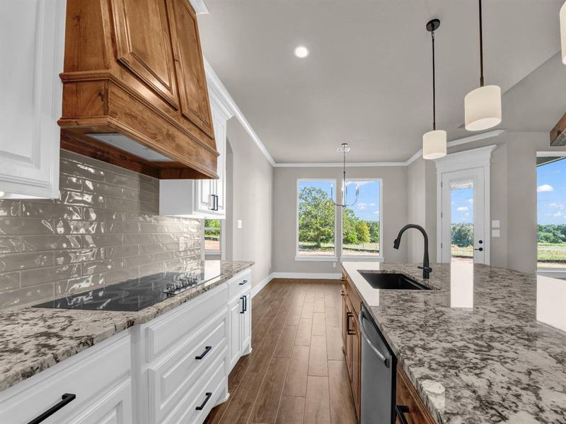 Kitchen with decorative light fixtures, light stone counters, brown cabinetry, dark wood-style floors, and crown molding
