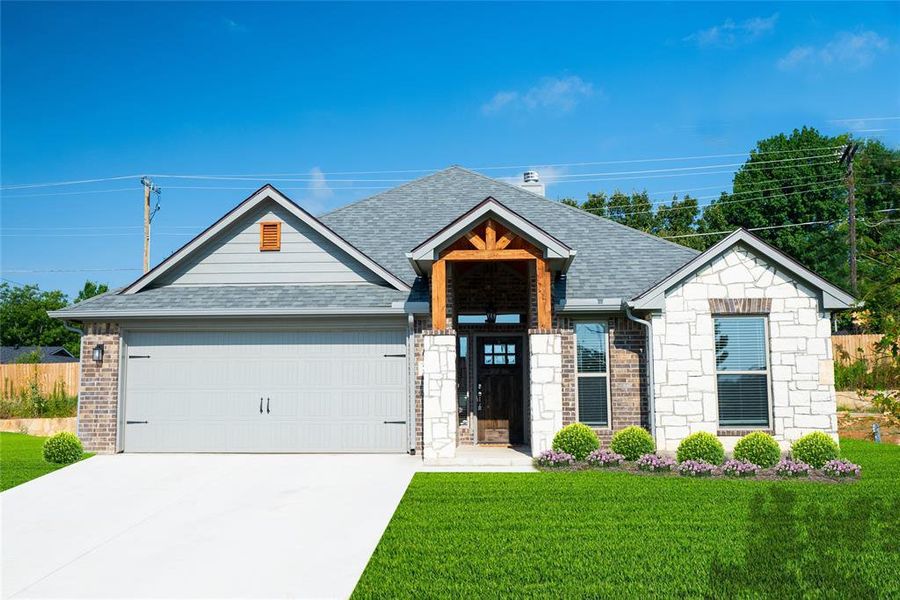 View of front of house featuring a front lawn and a garage