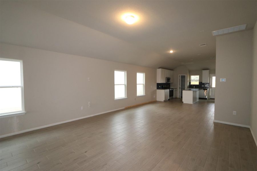 Unfurnished living room with lofted ceiling and light hardwood / wood-style floors