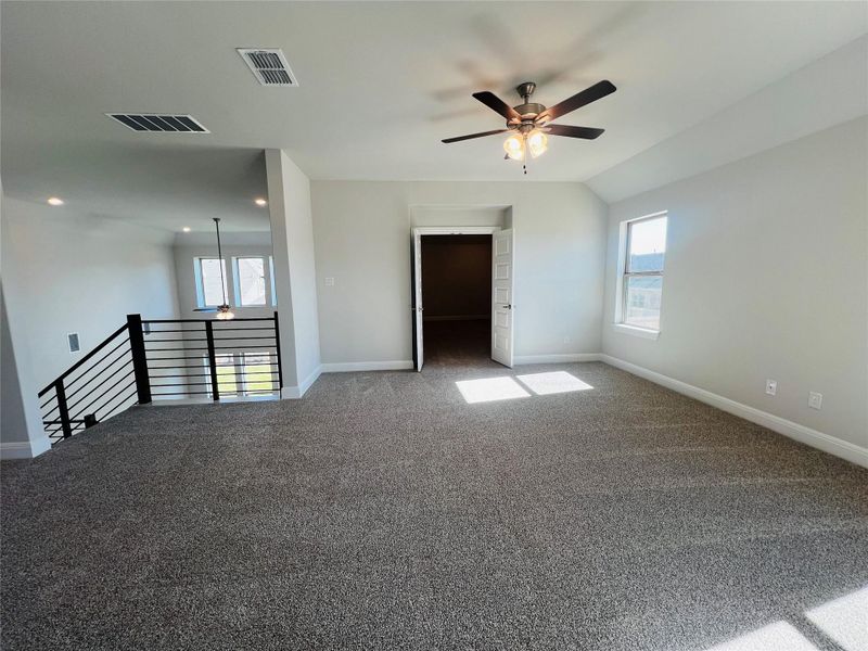Carpeted spare room featuring ceiling fan and healthy amount of natural light