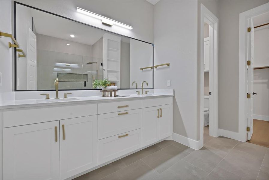 Full bathroom featuring double vanity, a stall shower, toilet, baseboards, and tile patterned floors