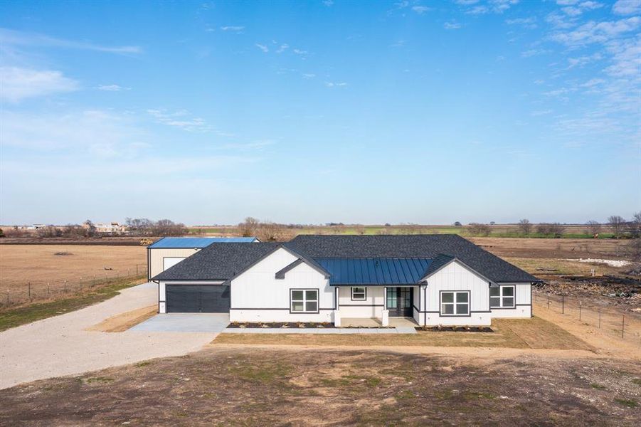 Modern inspired farmhouse with covered porch, a rural view, and a garage