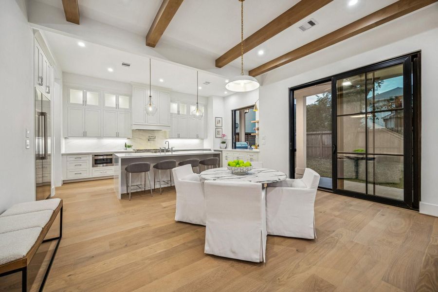 Breakfast Area with a 20" Wide Burnished Brass Bowl Pendant Light. There is a set of sliding doors that lead out the covered patio and a large yard with room enough for a pool.