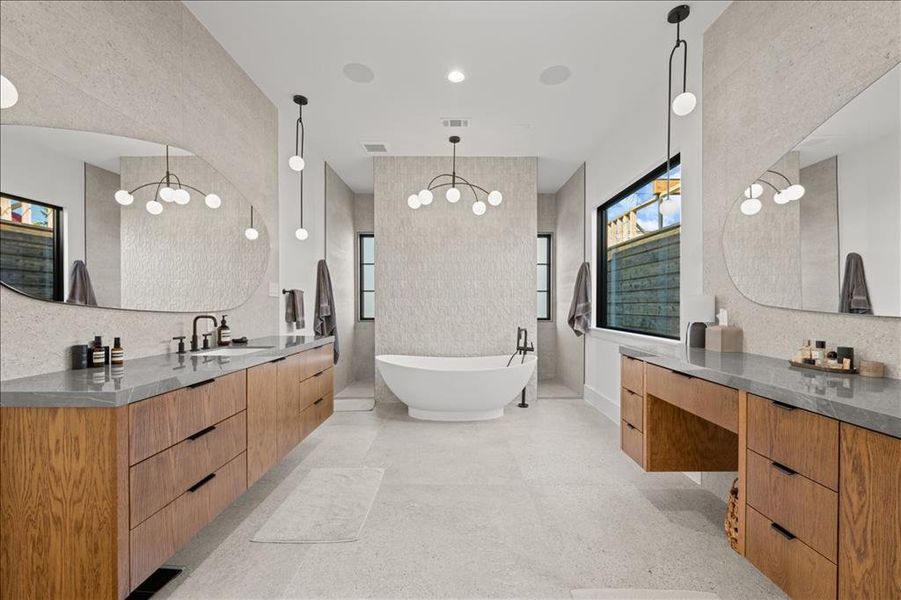 1st Primary full bath featuring a freestanding bath, two vanities, tile walls, plenty of natural light, and a chandelier