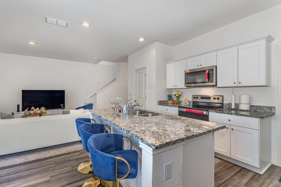 Kitchen with white cabinetry, stainless steel appliances, and a kitchen island with sink