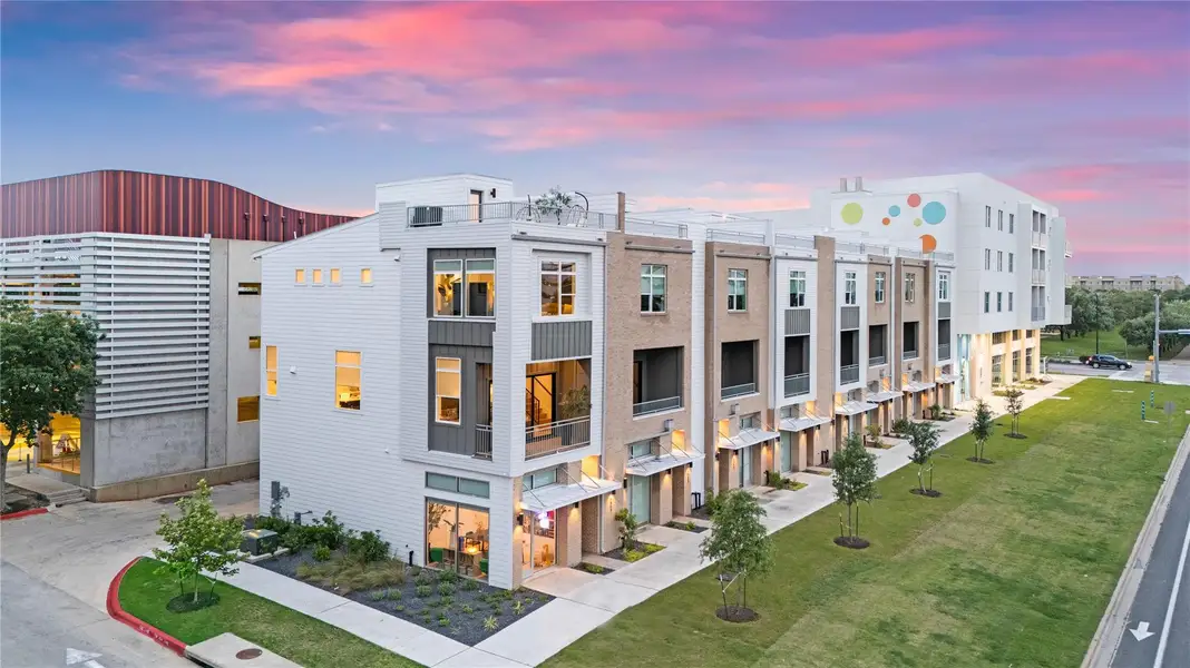 Modern multi-story facade featuring clean lines, large windows, and a rooftop deck