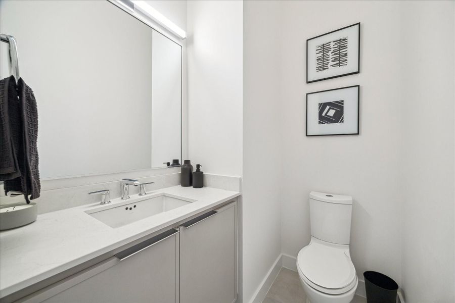 Minimalist powder bath showcasing clean architectural lines, a floating-style vanity, sleek chrome fixtures, and a full-height mirror that enhances light and dimension. Soft neutral tones and smooth wall finishes create a crisp, modern aesthetic. The streamlined layout maximizes function while maintaining a refined, contemporary feel consistent with the home’s elevated design throughout.