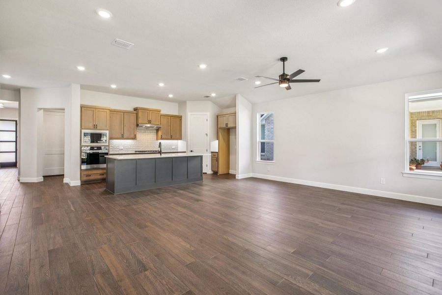 Kitchen featuring open floor plan, dark wood-type flooring, an island with sink, decorative backsplash, and recessed lighting Kitchen featuring open floor plan, dark wood-type flooring, an island with sink, decorative backsplash, and recessed lighting