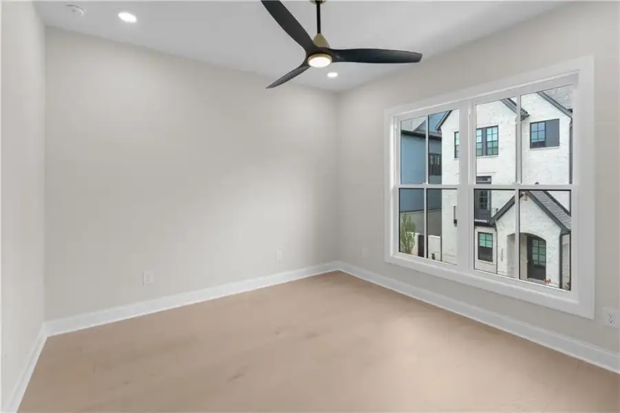 Light wood-finish flooring with white trim, recessed lighting, and a modern ceiling fan