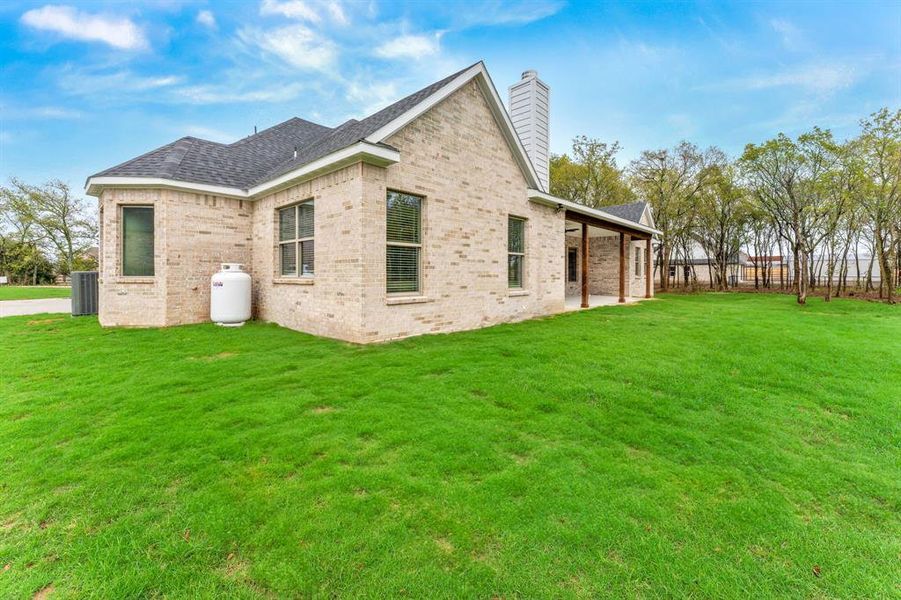 View of home's exterior featuring central AC unit and a lawn