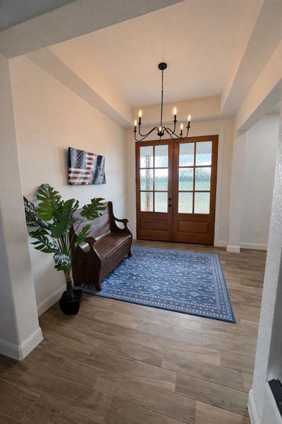 Foyer entrance with a chandelier, a raised ceiling, and wood finished floors Foyer entrance with a chandelier, a raised ceiling, and wood finished floors