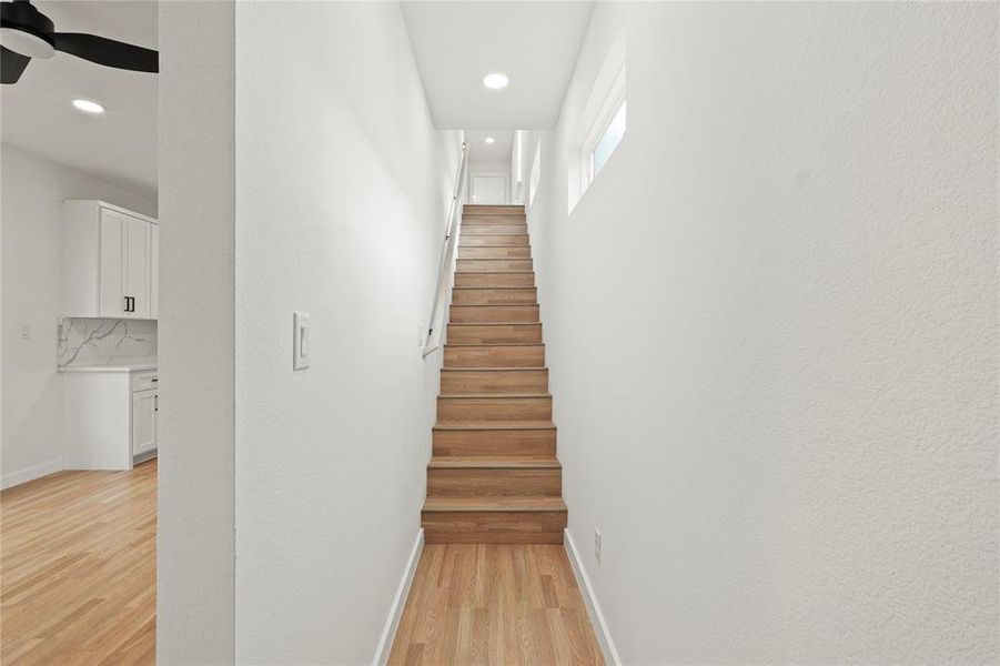 Staircase with hardwood / wood-style flooring and ceiling fan