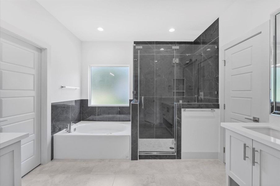 This modern bathroom features a spacious glass-enclosed shower with dark tile, a large soaking tub, and sleek white cabinetry, offering a clean and elegant design. This modern bathroom features a spacious glass-enclosed shower with dark tile, a large soaking tub, and sleek white cabinetry, offering a clean and elegant design.