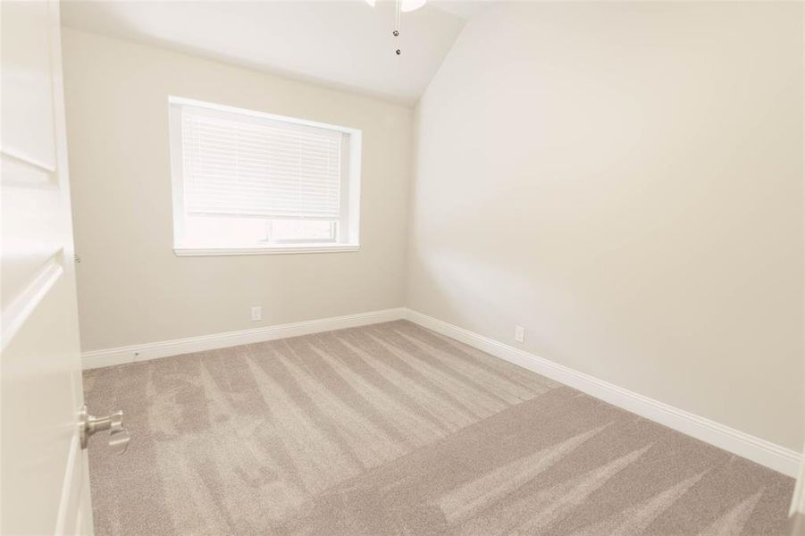 Spare room featuring lofted ceiling, ceiling fan, and carpet floors