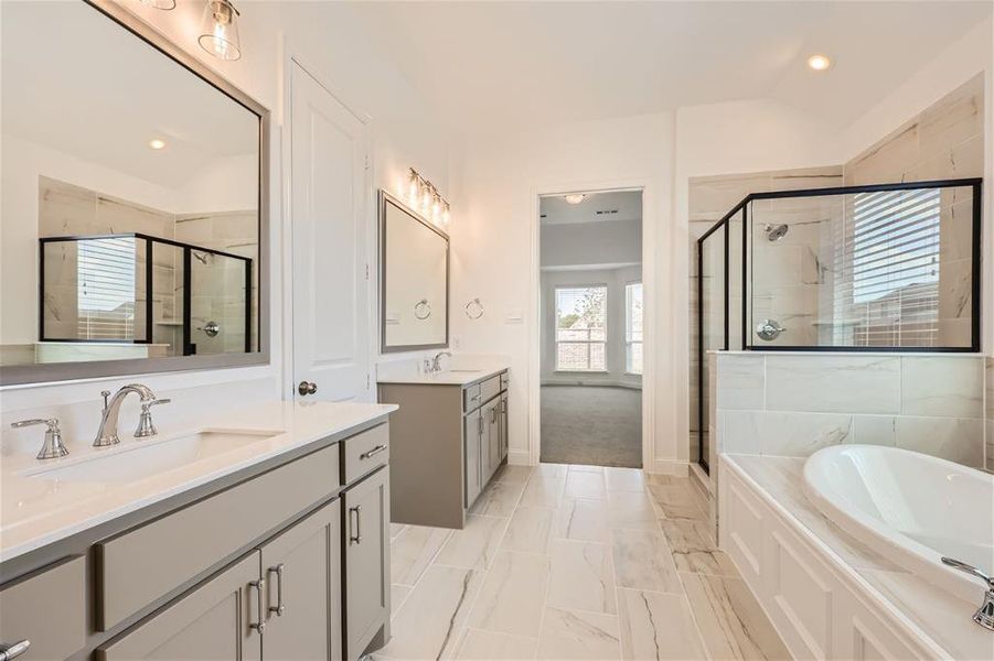 Bathroom featuring tile flooring, shower with separate bathtub, and double sink vanity