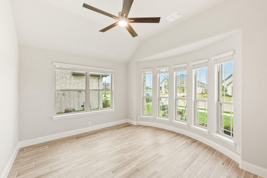 Empty room with vaulted ceiling, ceiling fan, light wood floors, and large windows with neighborhood views Empty room with vaulted ceiling, ceiling fan, light wood floors, and large windows with neighborhood views