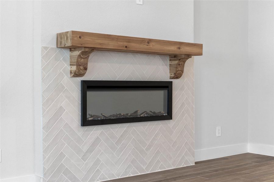 This contemporary fireplace setup highlights the living room's warm, transitional design. Elegant floor-to-ceiling herringbone tile surround in soft neutral tones with a thick, chunky natural wood mantel!