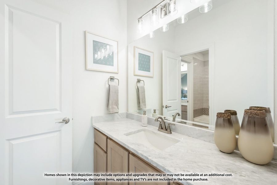 Bathroom vanity with marble countertop, single sink, light wood cabinets, and large mirror with overhead lighting. Bathroom vanity with marble countertop, single sink, light wood cabinets, and large mirror with overhead lighting.