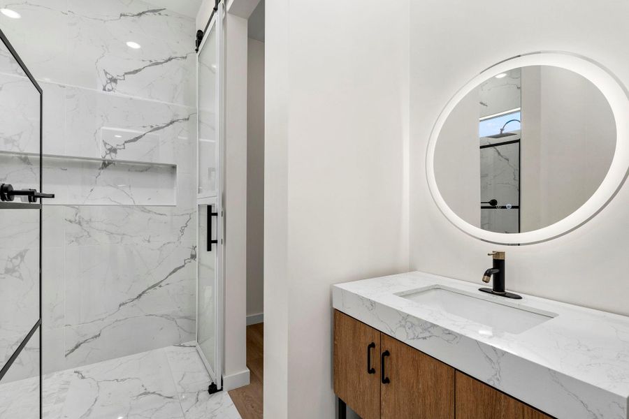 Bathroom with vanity and a marble finish shower