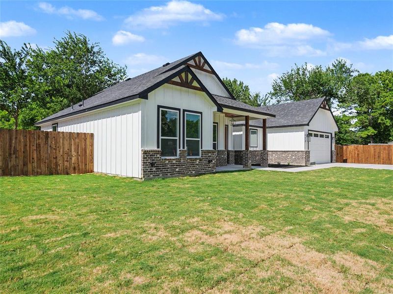 Modern farmhouse exterior featuring white vertical siding, dark brick accents, and a covered porch Modern farmhouse exterior featuring white vertical siding, dark brick accents, and a covered porch