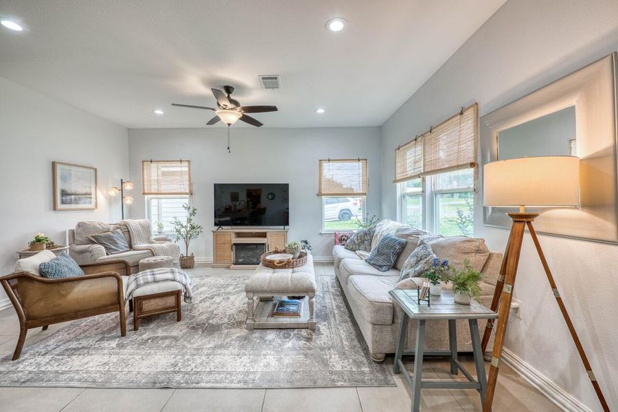 Spacious living area featuring light-toned walls and tile flooring