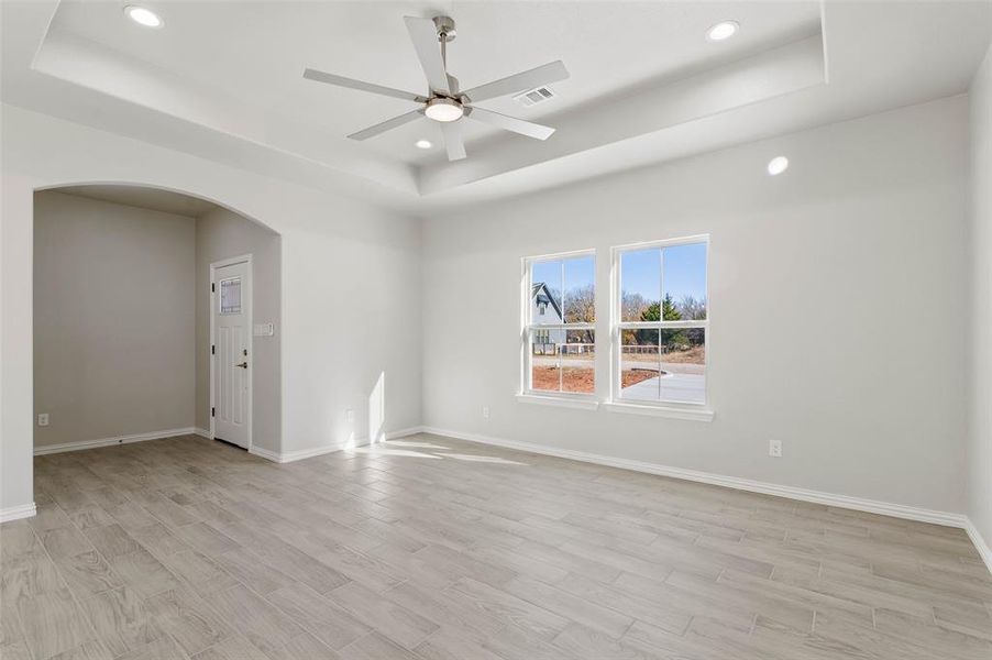 Spare room featuring ceiling fan, light wood-type flooring, and a tray ceiling Spare room featuring ceiling fan, light wood-type flooring, and a tray ceiling