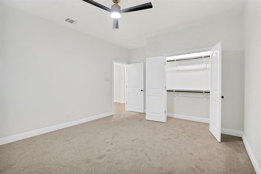 Unfurnished bedroom with ceiling fan, light colored carpet, and a closet