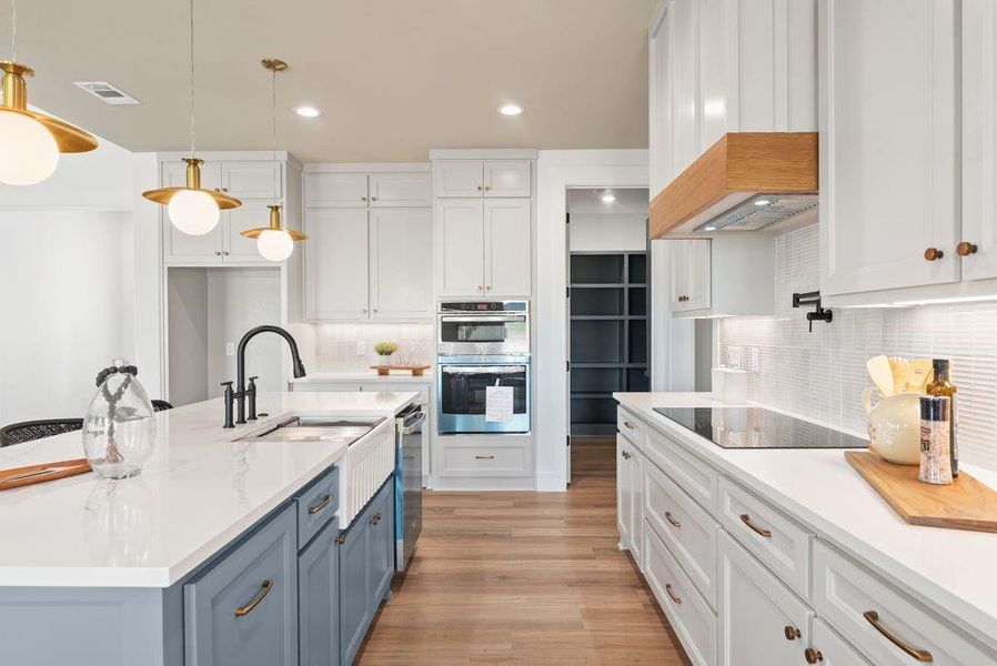 Kitchen with white cabinets, hanging light fixtures, backsplash, recessed lighting, and light stone countertops Kitchen with white cabinets, hanging light fixtures, backsplash, recessed lighting, and light stone countertops