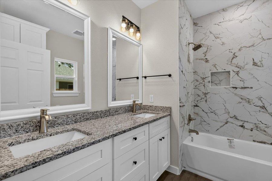 Polished granite counters and elegant marble-look tiling elevate this refined bathroom space. Polished granite counters and elegant marble-look tiling elevate this refined bathroom space.