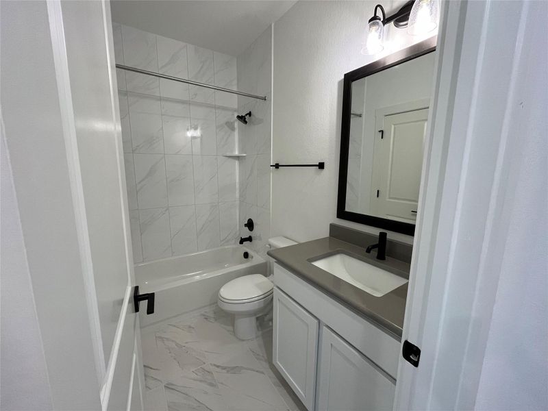 Upstairs full bath. Tile to ceiling. Framed mirror. Upgraded tile and quartz countertops