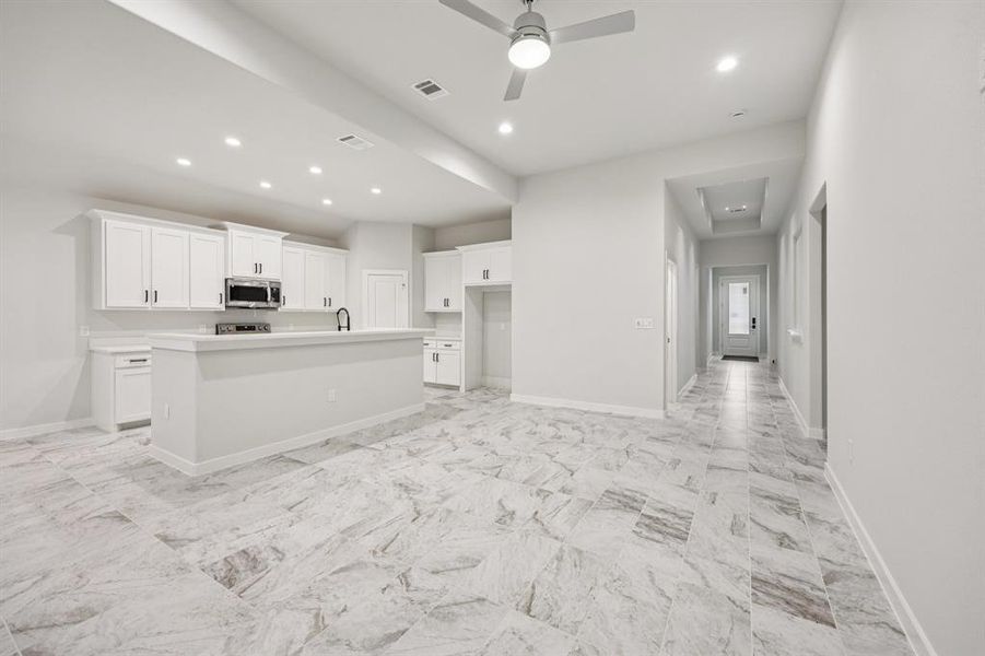 Kitchen featuring stainless steel microwave, white cabinets, ceiling fan, an island with sink, and recessed lighting Kitchen featuring stainless steel microwave, white cabinets, ceiling fan, an island with sink, and recessed lighting