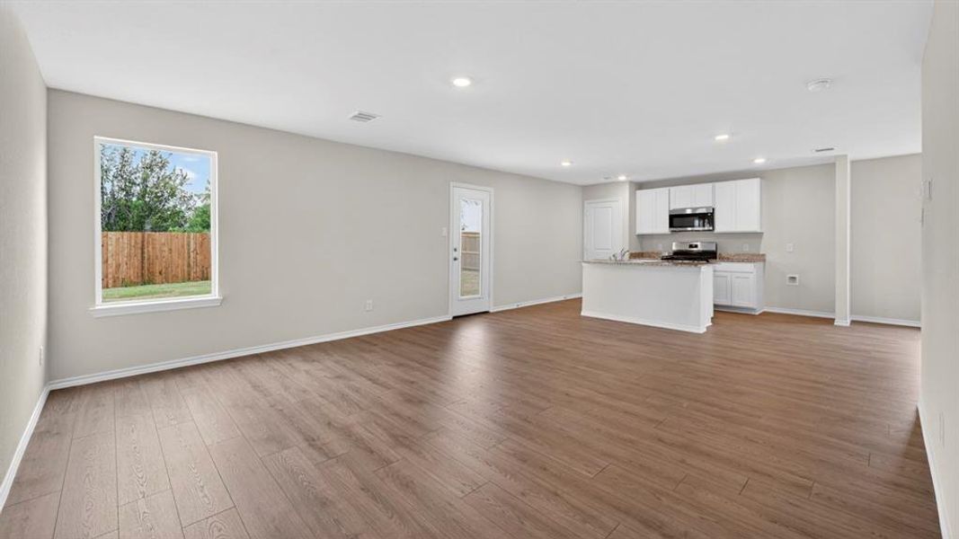 Spacious open concept living area featuring wood-finish flooring, recessed lighting, and neutral wall tones