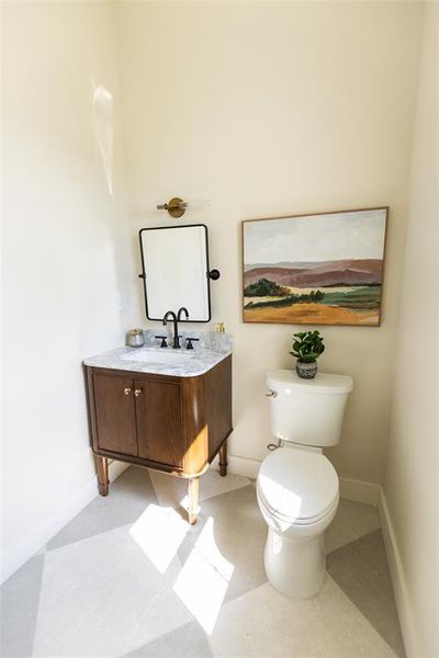 Powder room featuring a dark wood-finish vanity with a stone countertop, a rectangular mirror, and a wall-mounted light fixture