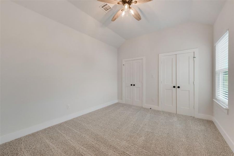 Unfurnished bedroom with carpet, lofted ceiling, and ceiling fan