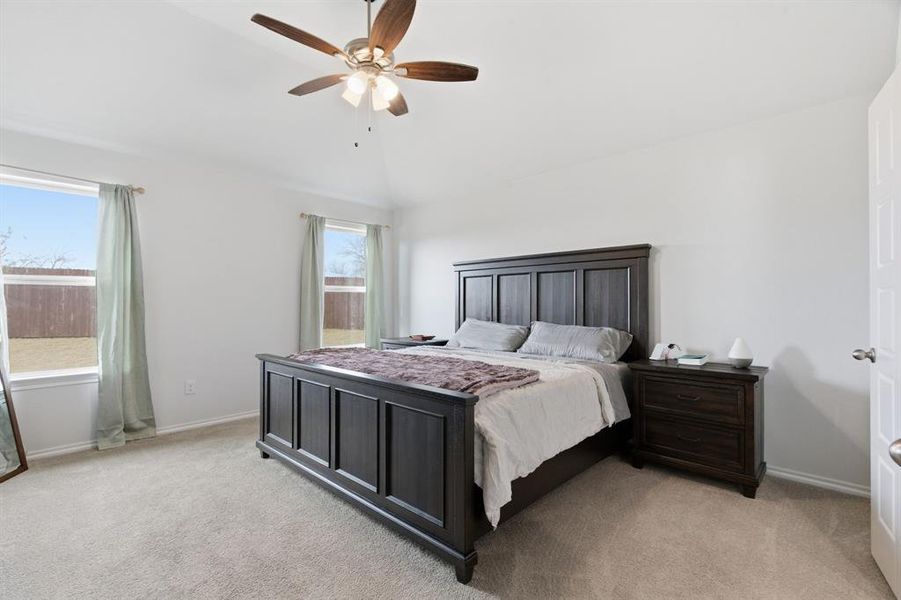 Bedroom with lofted ceiling, light carpet, and ceiling fan
