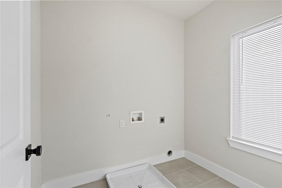 Laundry area featuring hookup for an electric dryer, light tile patterned flooring, hookup for a washing machine, and gas dryer hookup Laundry area featuring hookup for an electric dryer, light tile patterned flooring, hookup for a washing machine, and gas dryer hookup