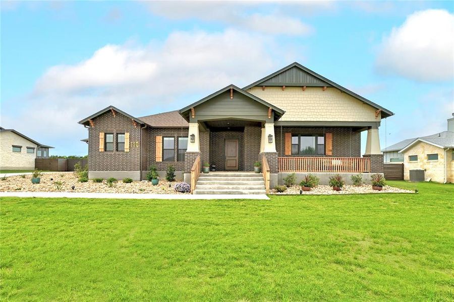 Craftsman house featuring covered porch, a front lawn, and brick siding