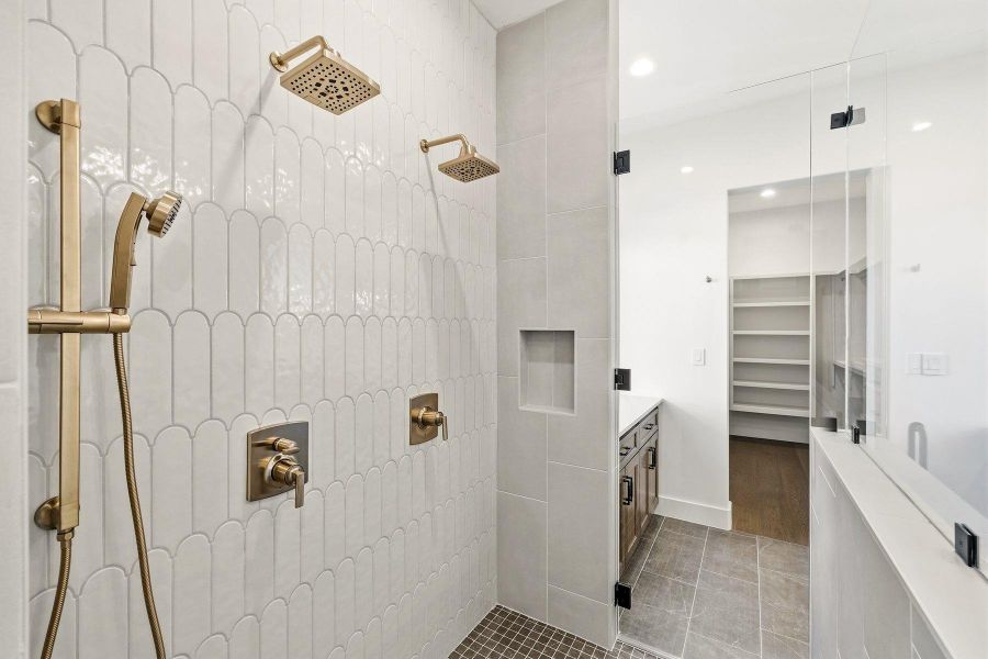 Bathroom with a walk in closet, vanity, tiled shower, dark tile patterned flooring, and recessed lighting