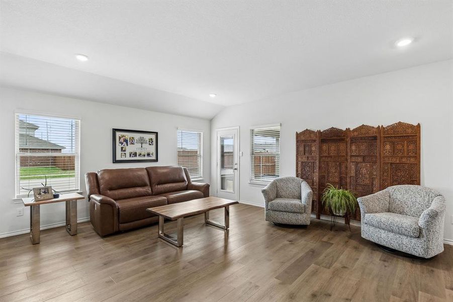 Living room featuring plenty of natural light, wood finished floors, vaulted ceiling, and recessed lighting Living room featuring plenty of natural light, wood finished floors, vaulted ceiling, and recessed lighting