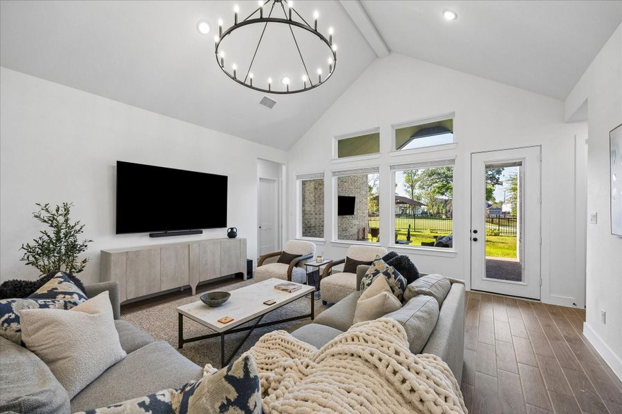 Vaulted family room anchored by a statement chandelier and expansive windows that frame backyard and greenbelt views. Seamless connection to the covered patio creates an easy indoor outdoor flow filled with natural light. Vaulted family room anchored by a statement chandelier and expansive windows that frame backyard and greenbelt views. Seamless connection to the covered patio creates an easy indoor outdoor flow filled with natural light.