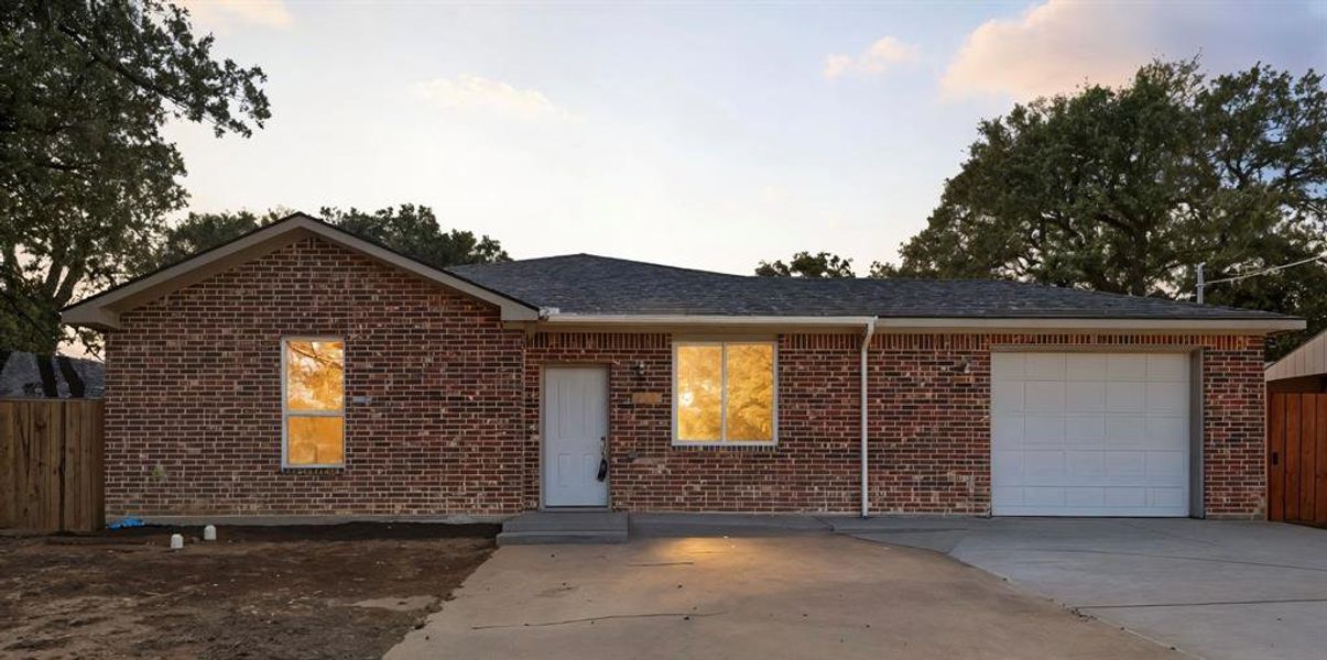 Single story home featuring an attached garage, brick siding, concrete driveway, and roof with shingles