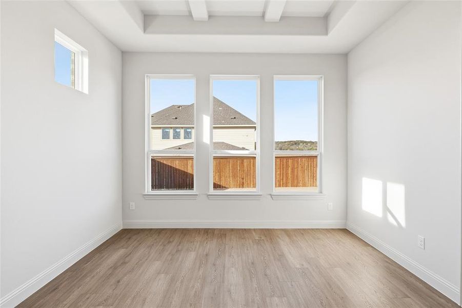 Unfurnished room featuring light wood-style floors and beamed ceiling Unfurnished room featuring light wood-style floors and beamed ceiling
