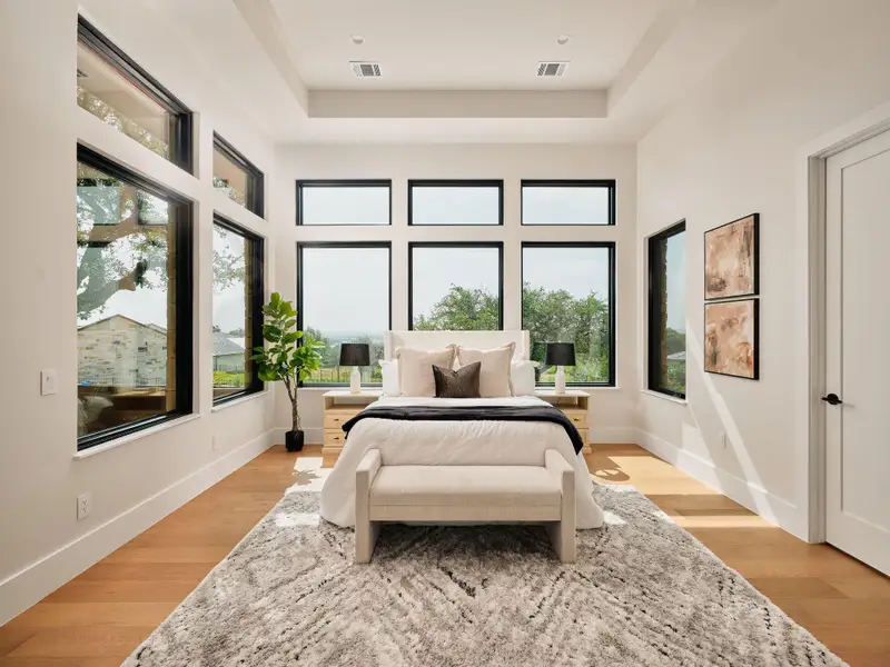 Floor-to-ceiling windows flood this primary bedroom with natural light and expansive outdoor views. Floor-to-ceiling windows flood this primary bedroom with natural light and expansive outdoor views.