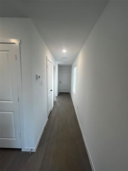 Hallway featuring wood-finish flooring, recessed lighting, and crisp white walls Hallway featuring wood-finish flooring, recessed lighting, and crisp white walls