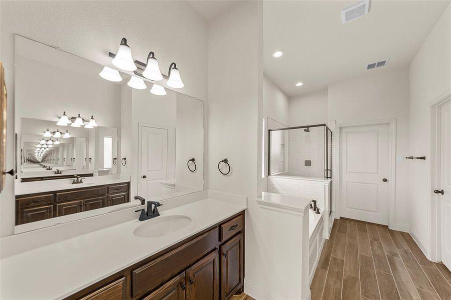Bathroom featuring a shower stall, vanity, wood finish floors, recessed lighting, and a bath Bathroom featuring a shower stall, vanity, wood finish floors, recessed lighting, and a bath
