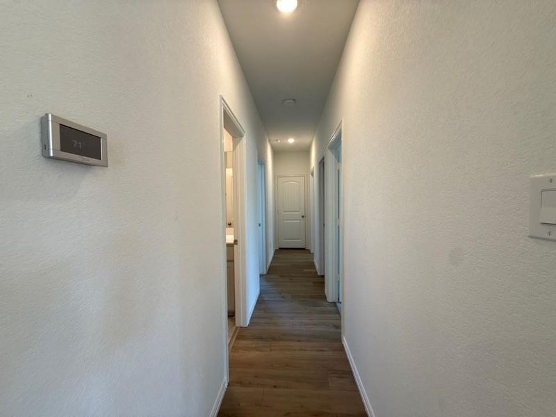 Hall with a textured wall, recessed lighting, and dark wood-type flooring
